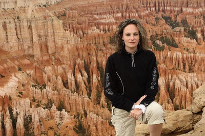 Portrait of smiling young woman standing on rock