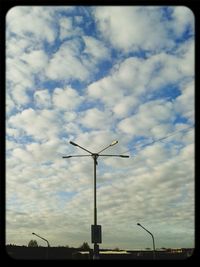 Low angle view of wind turbine against cloudy sky