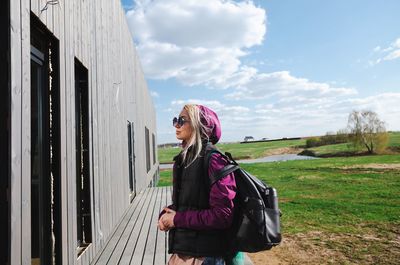 Rear view of woman standing on field against sky