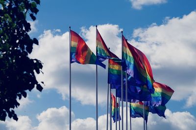 Low angle view of rainbow flags against sky