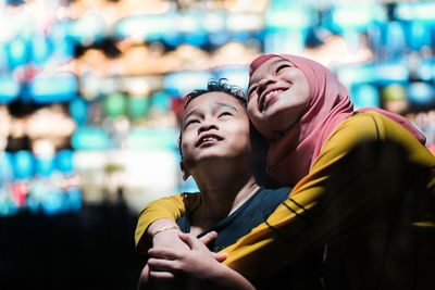 Close-up of smiling girl embracing brother while looking up