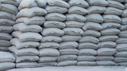 A lot of cement mortars are lying on the white ground in an arrangement to show stock of cement