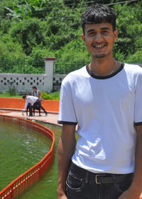 Portrait of a handsome guy wearing white t-shirt with standing beside of lake 