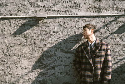 Young man looking away against wall