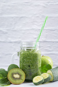 Green detox smoothie in a jar on white background. vertical format. healthy nutrition concept.