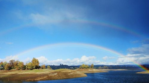 Scenic view of rainbow over landscape against sky