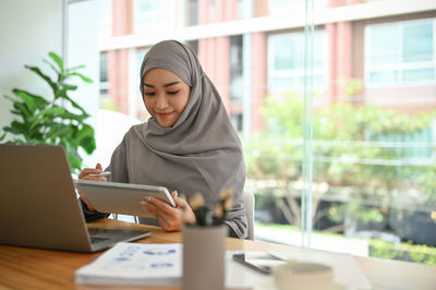 Young businesswoman wearing hijab holding digital tablet
