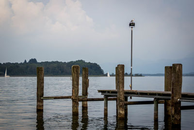 Wooden posts on pier over sea against sky