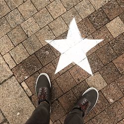 Low section of man standing by star shape on footpath