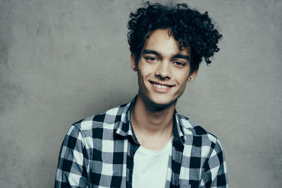 Portrait of smiling young man standing against wall