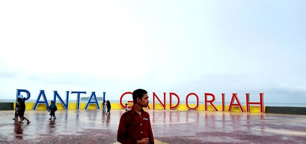 Full length of woman standing by sign against sky