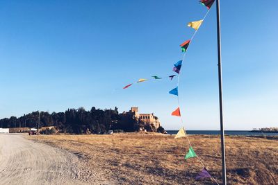 Buntings waving on pole at beach against blue sky