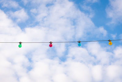 Low angle view of light bulbs hanging against sky