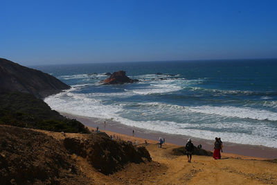 People on beach against clear sky