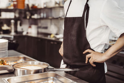 Manlig kock med händerna på höften i restaurangkök