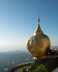 Temple by building against clear sky