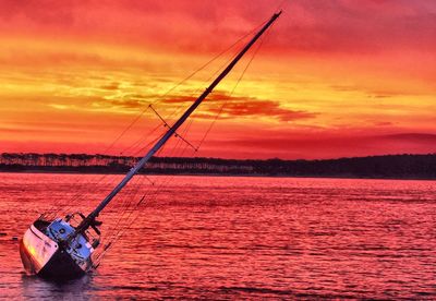 Sailing boat in sea against sky during sunset