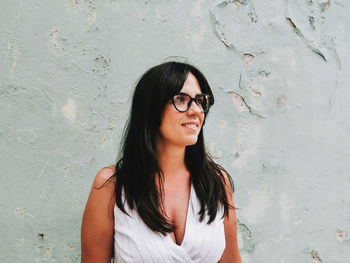 Portrait of a young woman wearing eyeglasses, smile, solid background.