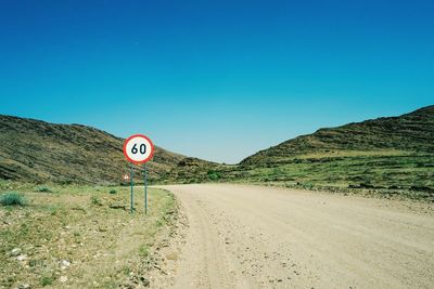 Low angle view of road sign against clear blue sky