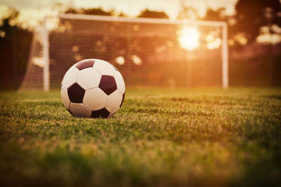 Close-up of soccer ball on field at sunset