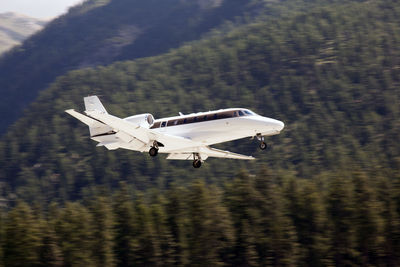 Airplane flying over landscape against sky