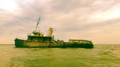 Abandoned ship in sea against sky