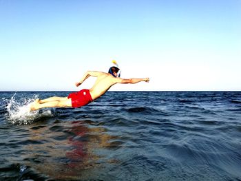 Man diving into water against clear sky