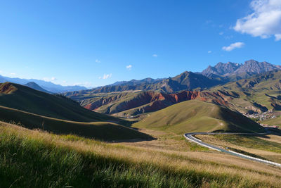 Scenic view of landscape and mountains against blue sky