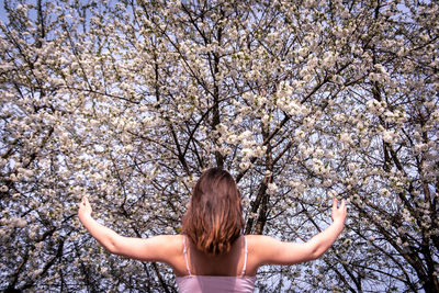 Rear view of woman against cherry blossom tree