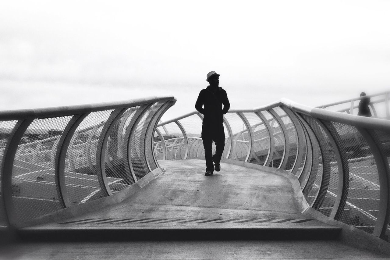 transportation, rear view, railing, men, clear sky, bridge - man made structure, full length, built structure, architecture, sky, lifestyles, walking, mode of transport, travel, copy space, the way forward, leisure activity, standing