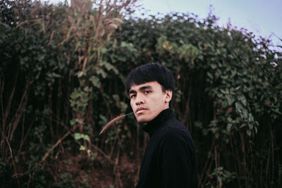 Portrait of young man standing in forest