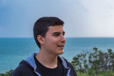 Portrait of young man looking away against sky