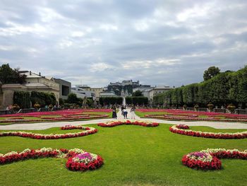 Scenic view of garden in park against cloudy sky