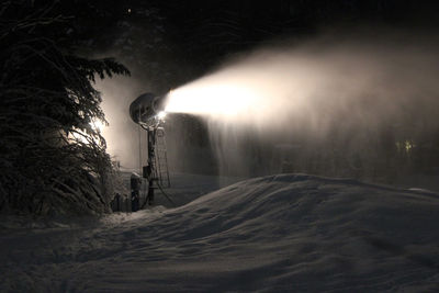 Illuminated trees on snow against sky at night