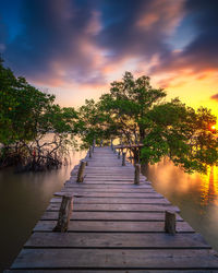 Pier amidst lake against sky during sunset