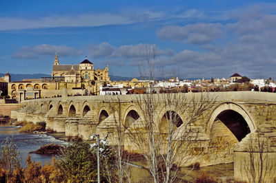 Arch bridge over buildings in city against sky