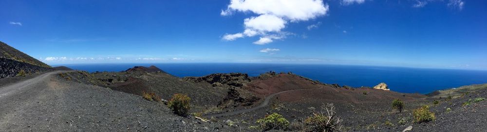 Panoramic view of sea and mountains against blue sky