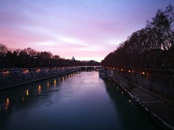 Reflection of illuminated trees in water against sky