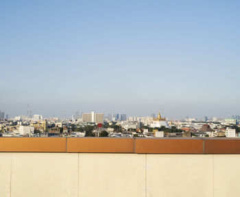 Bangkok city with lots of high building and temple combine together behind the orange wall.