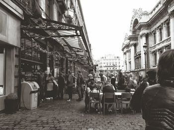 People sitting on street against buildings