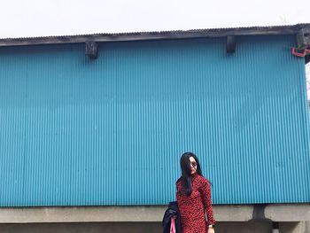 Woman wearing sunglasses while standing against wall