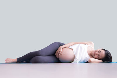 Midsection of woman lying down against white background