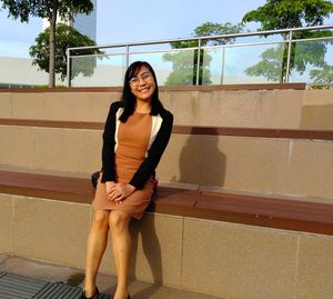 Portrait of young woman standing against railing