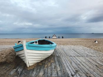 Boat moored on beach against sky