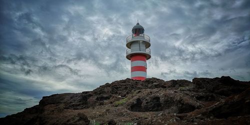 Low angle view of lighthouse by building against sky