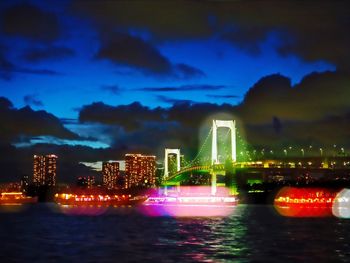 Illuminated city against cloudy sky at dusk