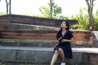 Full length of woman sitting against wall