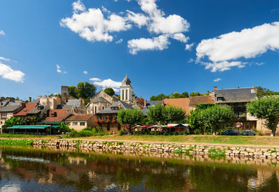 Houses by river and buildings against sky