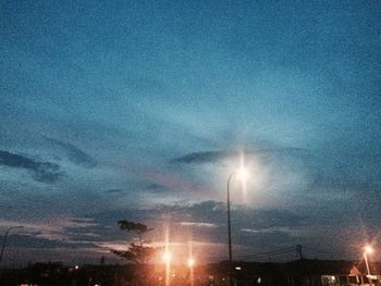 Illuminated street light against sky at night