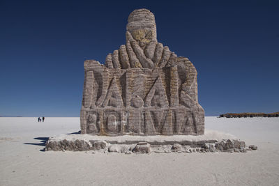Low angle view of sculpture on sand against sky